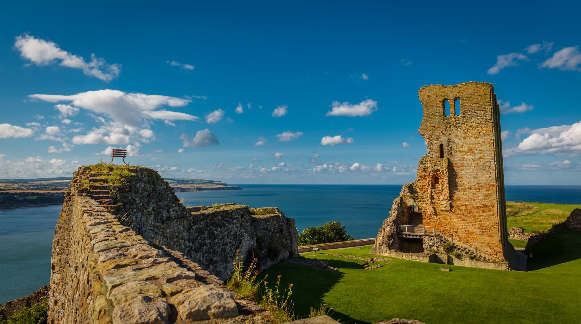 The historic ruins of Scarborough Castle on a headland, bathed in warm golden hour light.