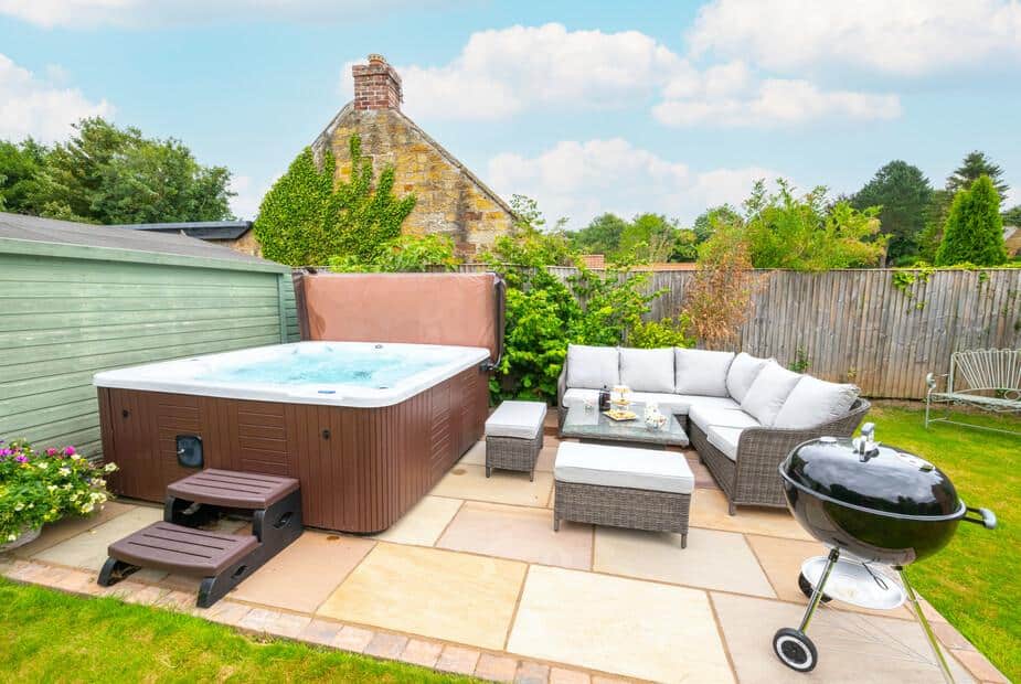 Cottage patio with hot tub, rattan seating and charcoal barbecue grill