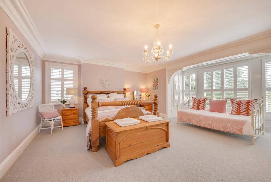 Bedroom with wooden bed frame and bay window with shutters