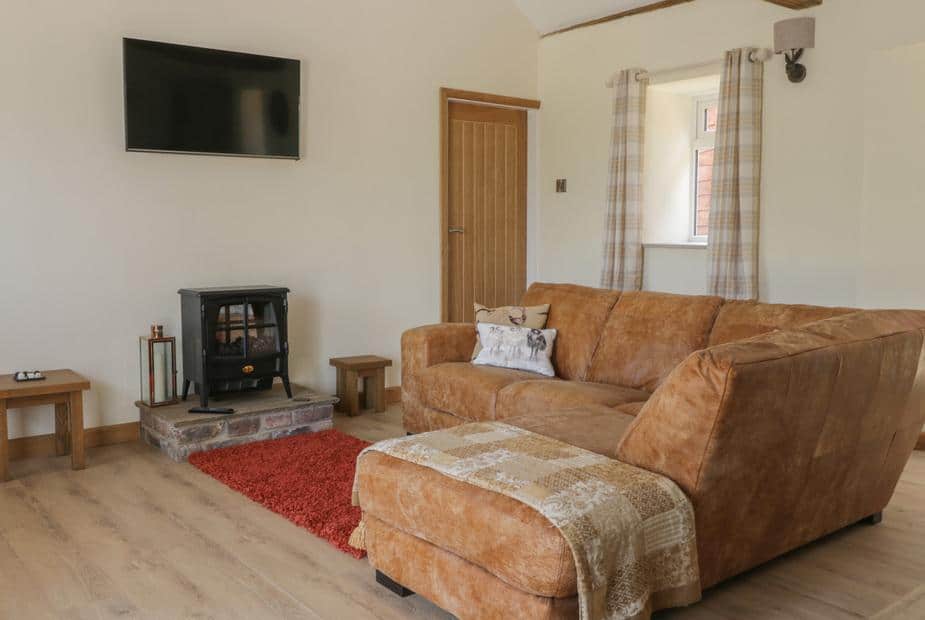 Living room with brown sofa, electric stove, and wall-mounted TV