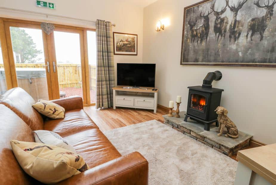 Lounge with wood burner, leather sofa and TV by patio doors