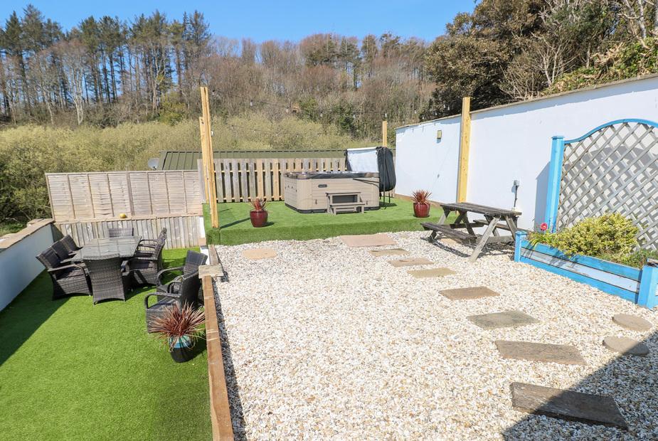 Cottage garden with gravel path, patio seating and hot tub