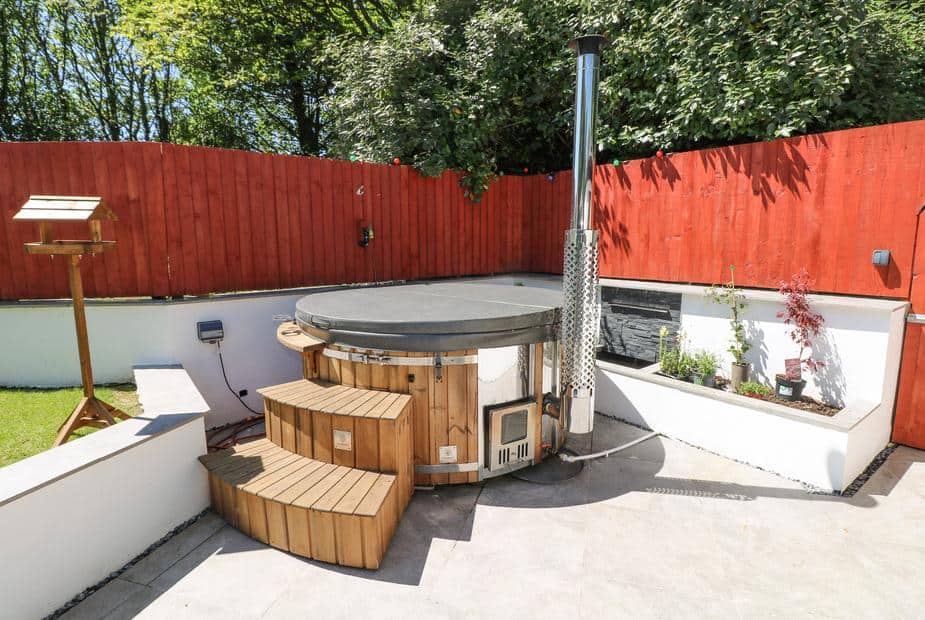 Cottage patio with wooden hot tub and red fence