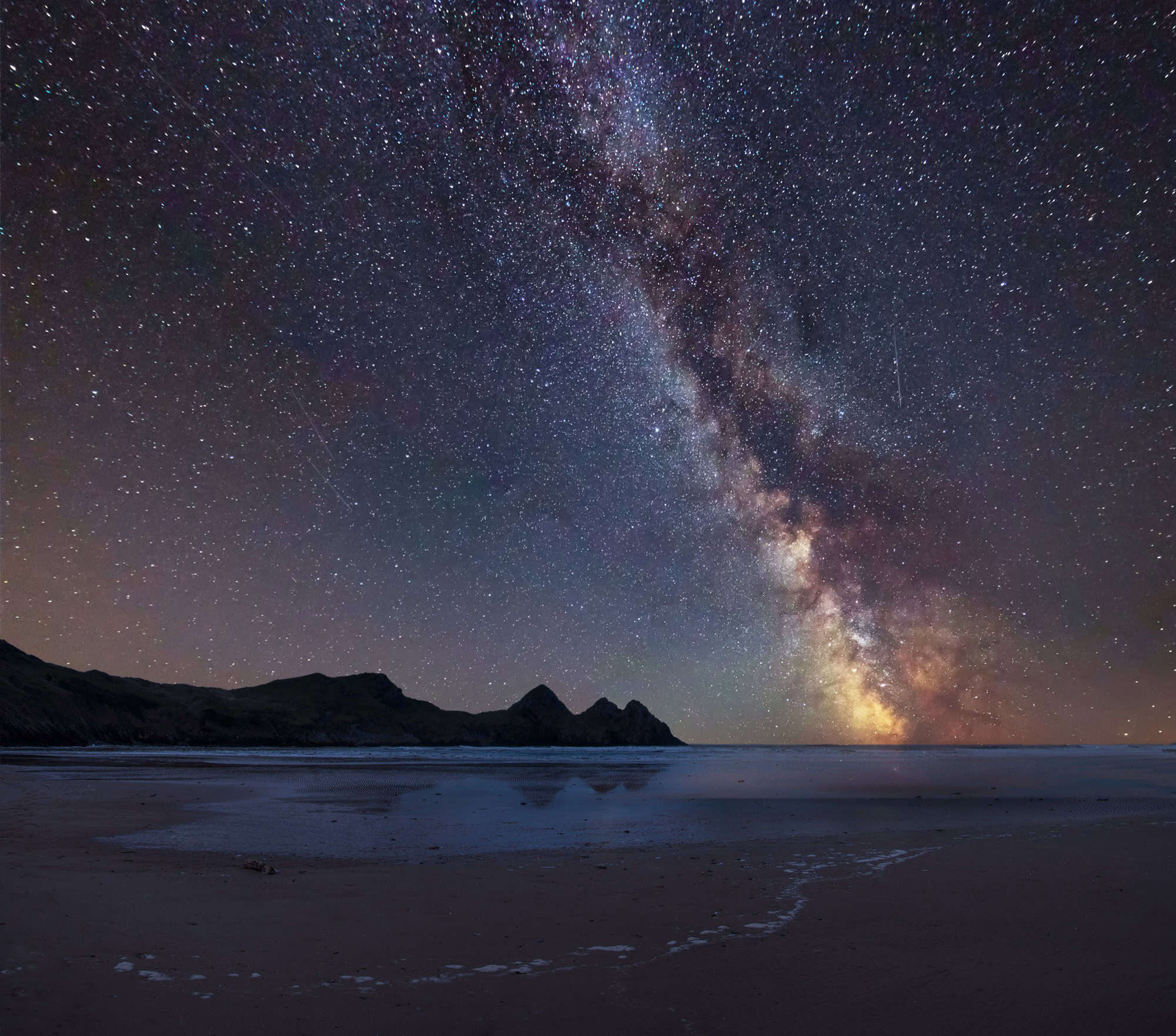 The Milky Way shining over the iconic Three Cliffs Bay on the Gower coast, South Wales.