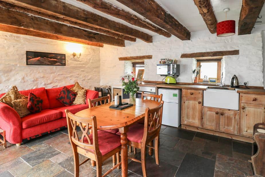 Kitchen and living area with wooden beams and red sofa