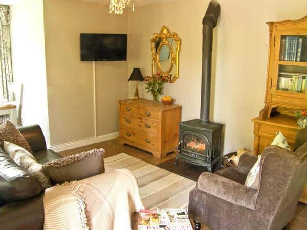 Cottage living room with wood burner and wall-mounted television