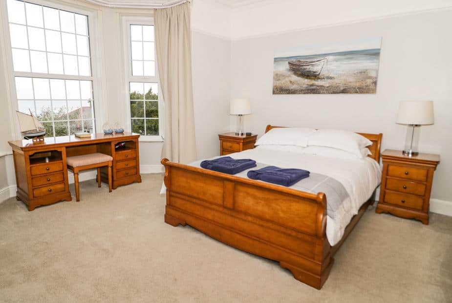 Bedroom with sleigh bed and wooden desk by bay window