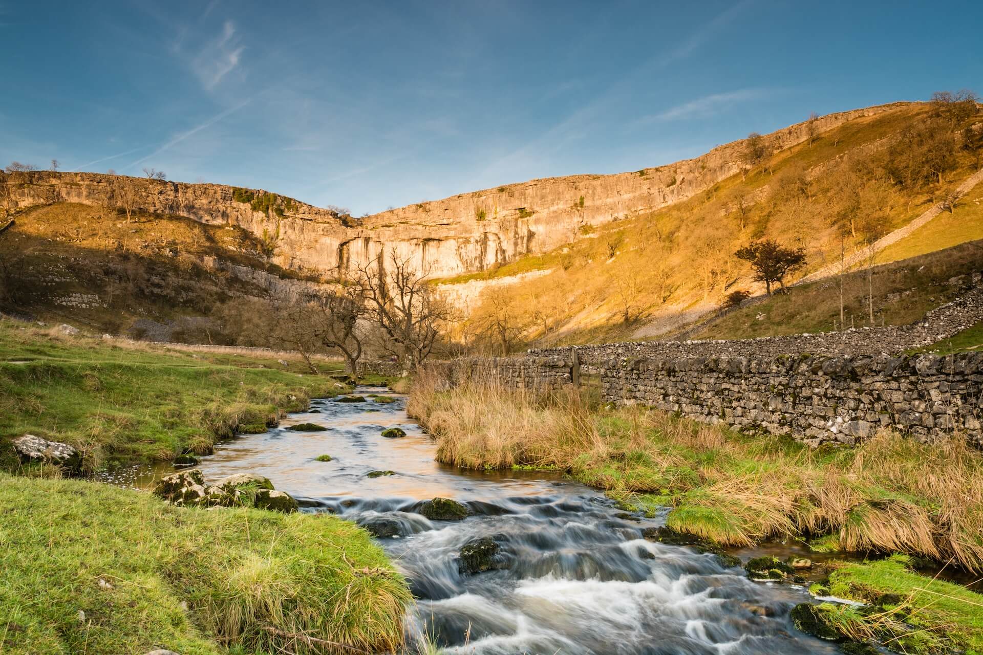 The dramatic limestone cliffs of Malham Cove and Malham Beck in the Yorkshire Dales National Park.