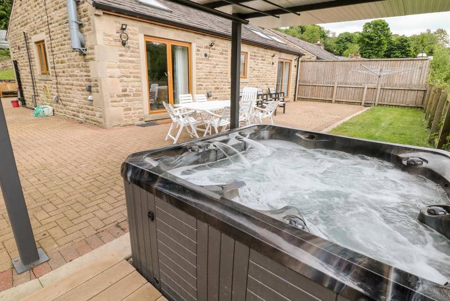 Cottage patio with outdoor hot tub and white dining table