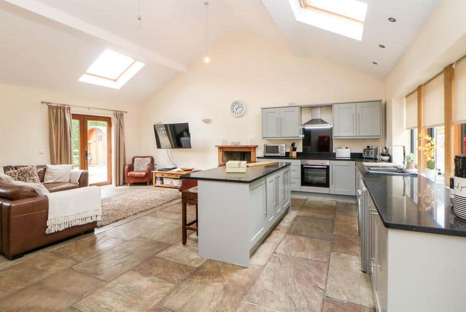 Cottage kitchen with island and adjoining lounge area with sofa and TV