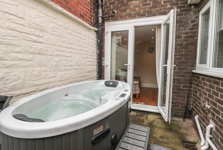 Cottage patio with hot tub next to open French doors