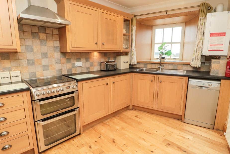 Cottage kitchen with wooden cabinets, range cooker and window above sink