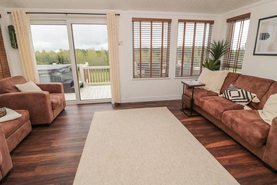 Lodge living room with brown sofas and sliding door to deck with hot tub
