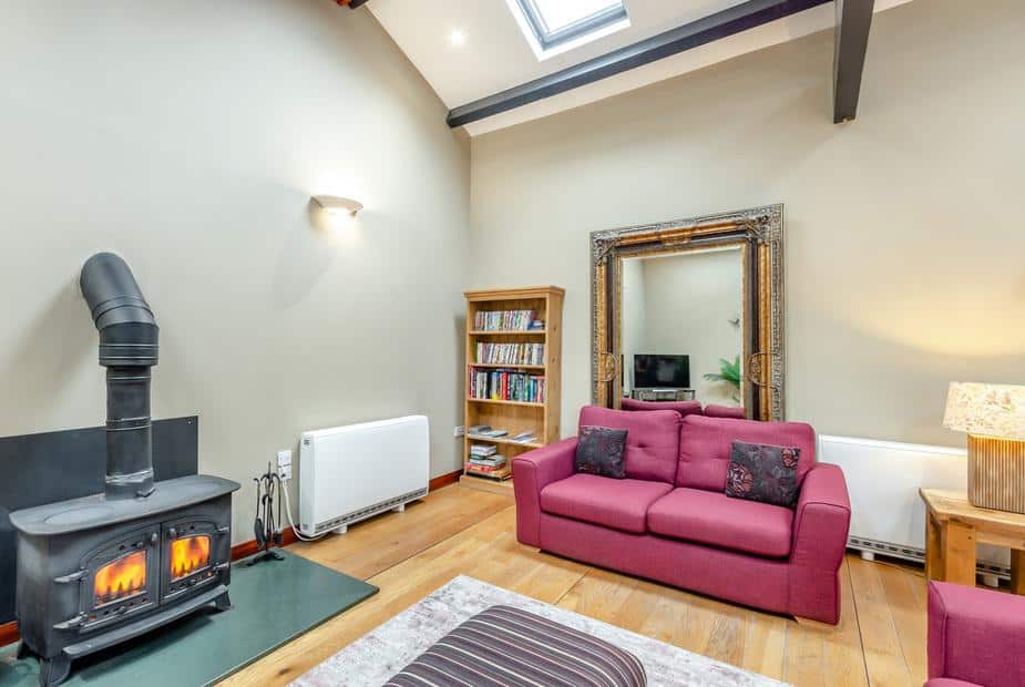 Cottage lounge with log burner, red sofa and bookcase