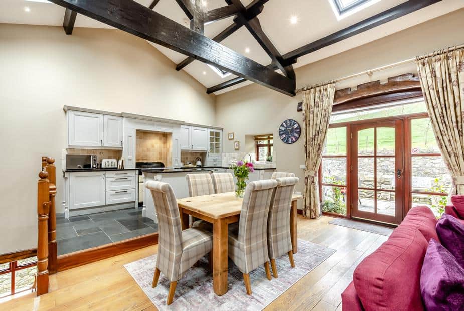 Cottage kitchen and dining area with exposed beams and French doors to garden