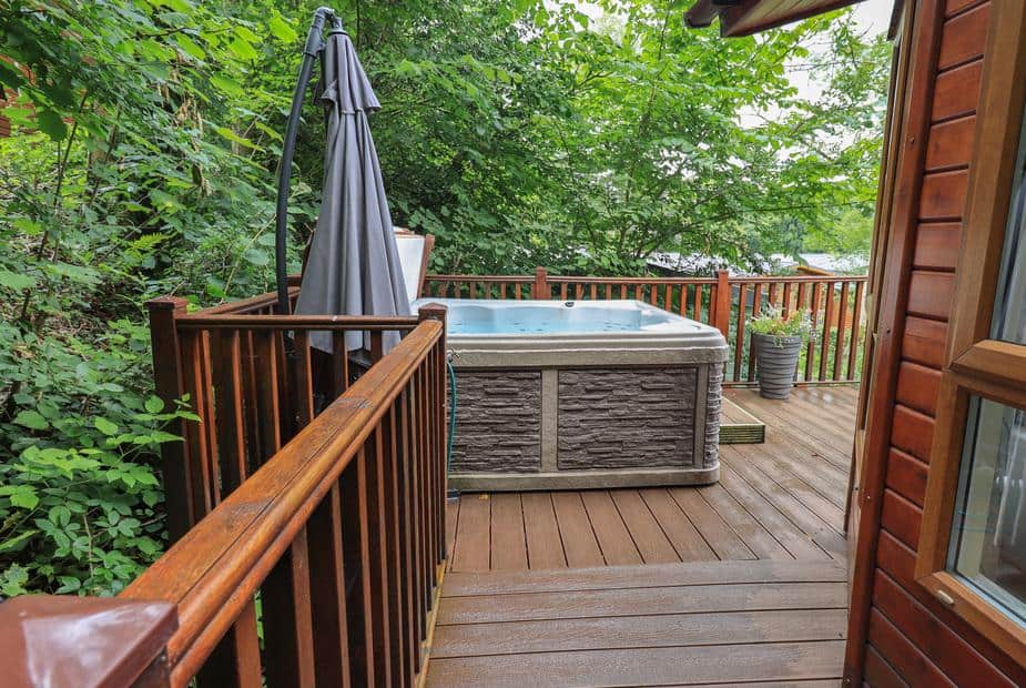 Lodge decking with hot tub and outdoor umbrella by wooden railing