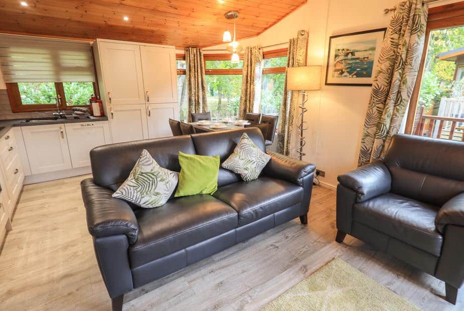 Lodge lounge with leather sofa, armchair and view of kitchen and dining table