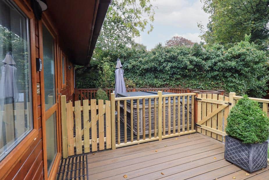 Lodge deck with hot tub behind wooden gate and potted shrub
