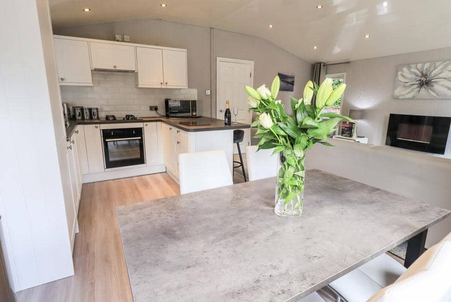 Lodge kitchen and dining area with table, vase of flowers and integrated appliances