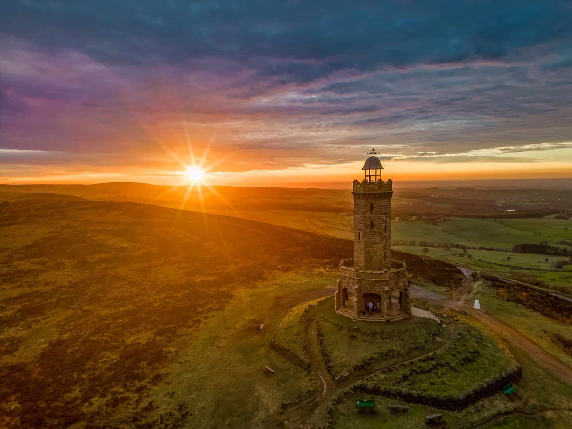 Golden sunset creates a dramatic sunburst behind Darwen Tower, overlooking the rolling Lancashire countryside.
