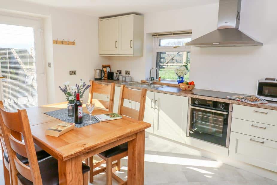 Cottage kitchen with dining table, oven and sink under window
