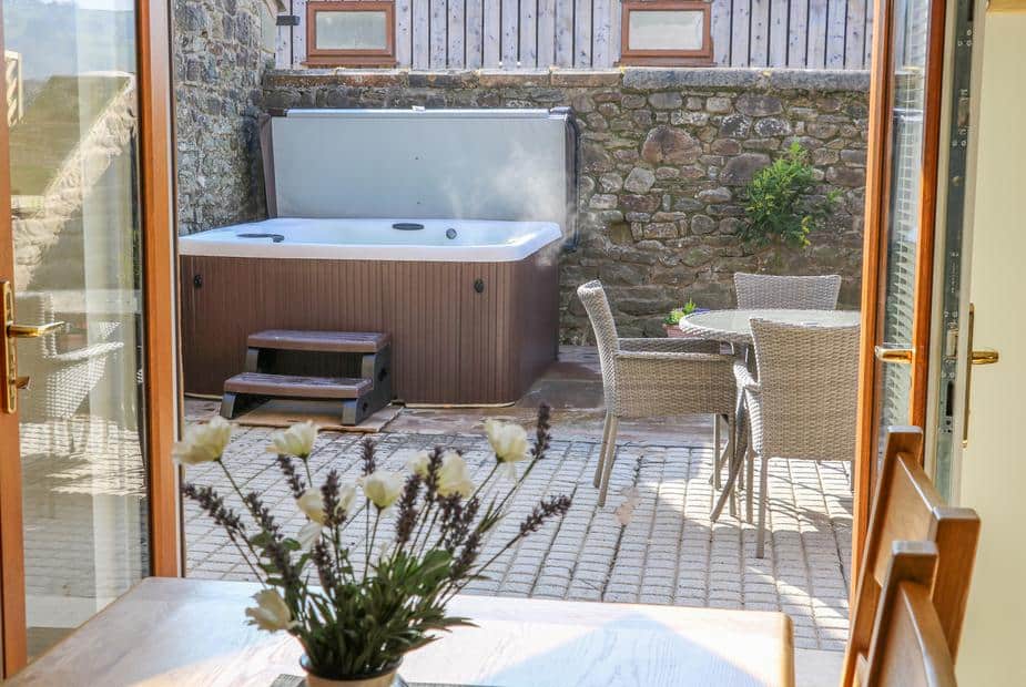 Cottage patio with hot tub and wicker table and chairs viewed from inside
