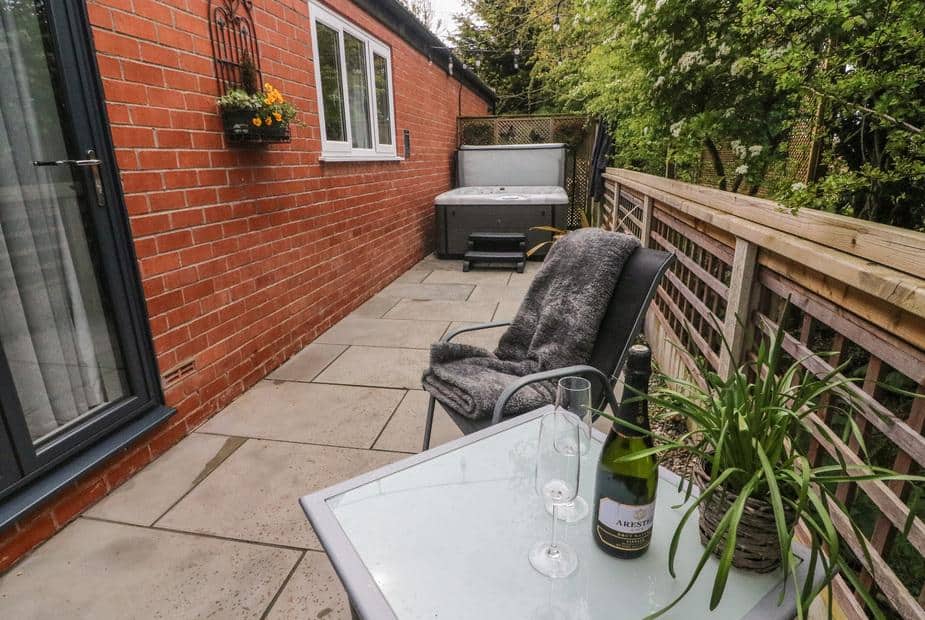 Lodge patio with hot tub, chair and table with wine and glasses