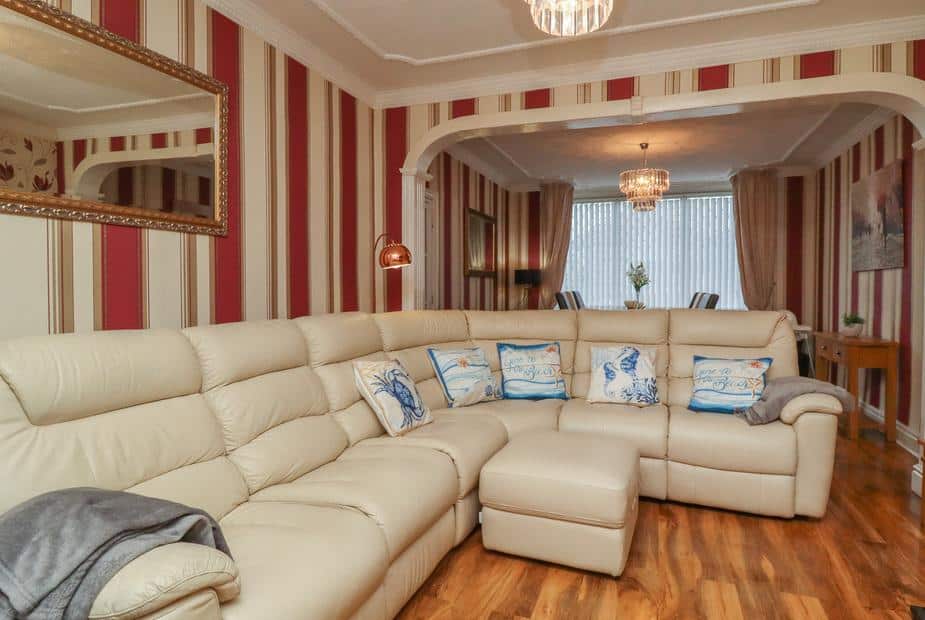 Cottage living room with cream corner sofa and striped wallpaper