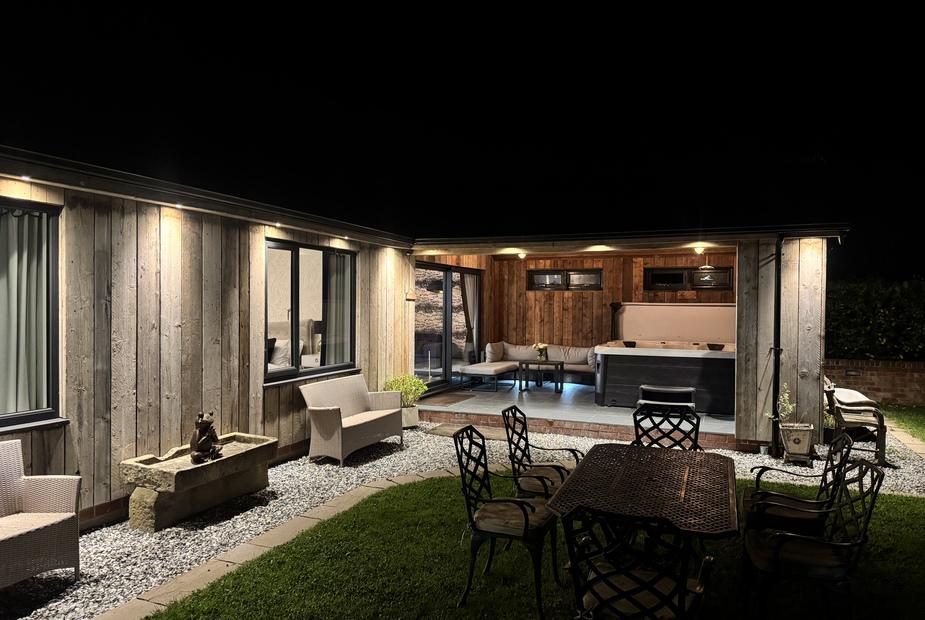 Lodge garden at night with outdoor seating and covered hot tub area