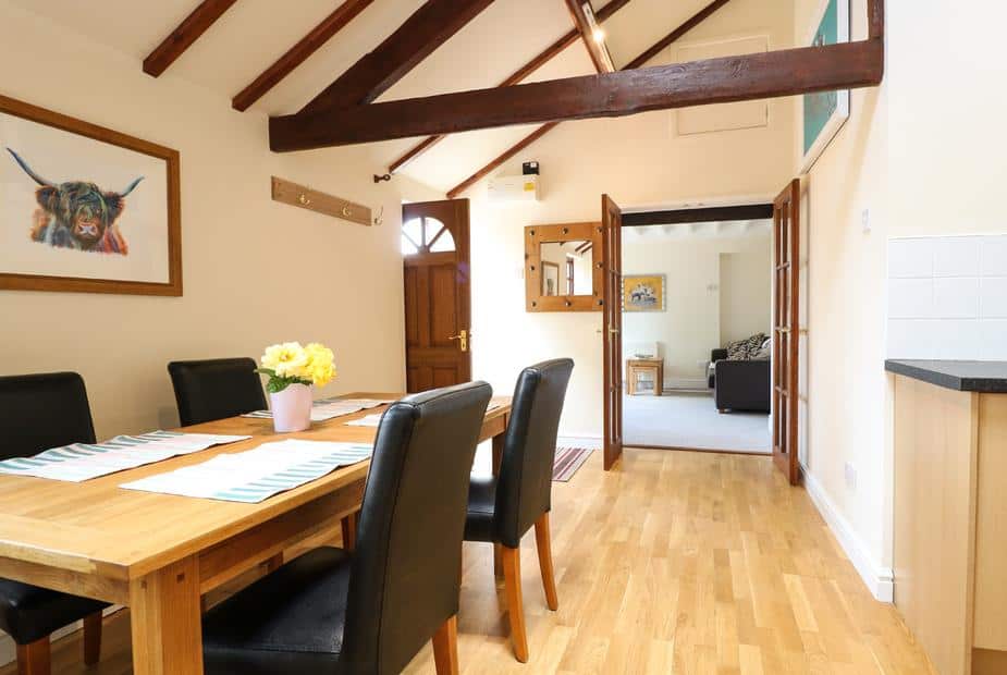 Cottage dining area with wooden table, black chairs and exposed ceiling beams