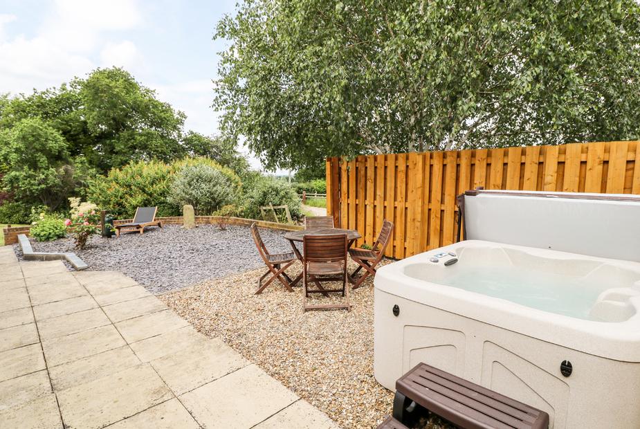 Cottage garden with hot tub, wooden table and chairs, gravel and patio area