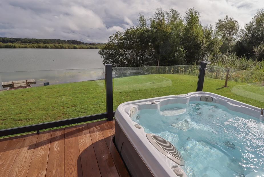 Lodge decking with hot tub overlooking lake and grassy area