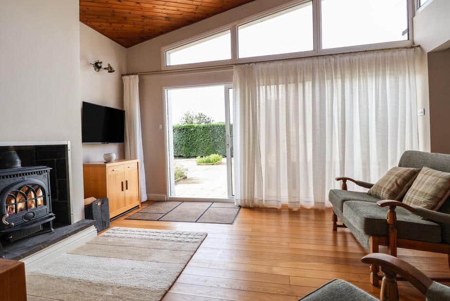 Lodge living room with wood burner, sofa and patio door with garden view