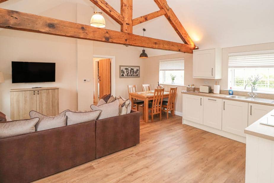 Cottage open-plan living area with sofa, dining table, kitchen and exposed wooden beams