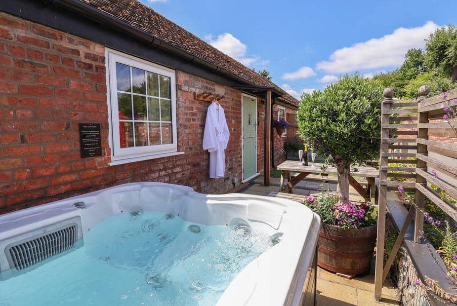 Cottage patio with hot tub, bench seating and potted plants