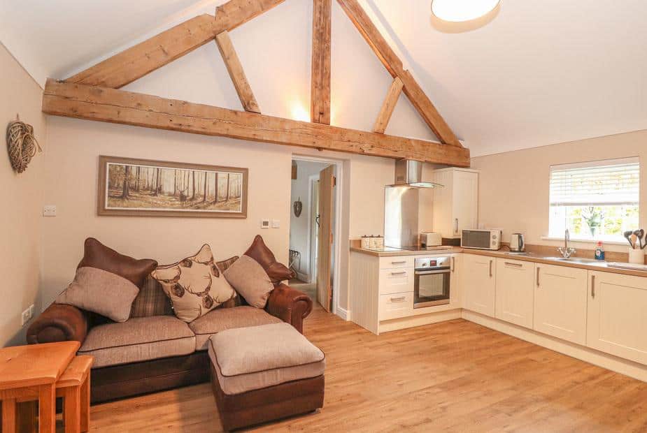Cottage open-plan lounge and kitchen with exposed wooden beam and sofa