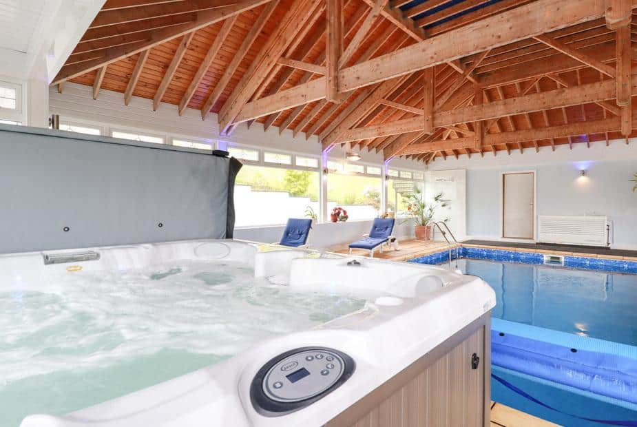 Cottage indoor pool room with hot tub and wooden vaulted ceiling