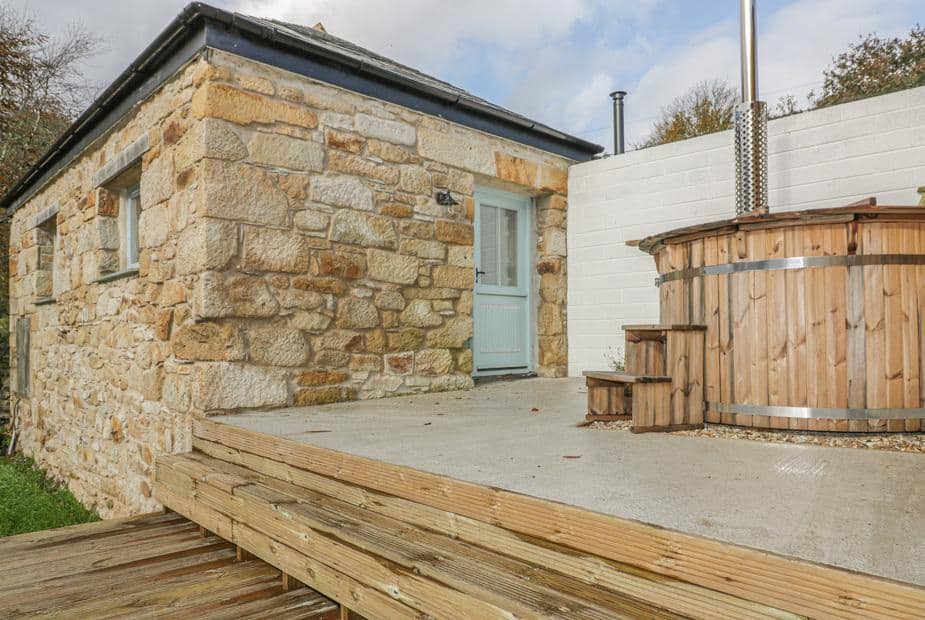 Cottage stone exterior with wooden hot tub on raised decking