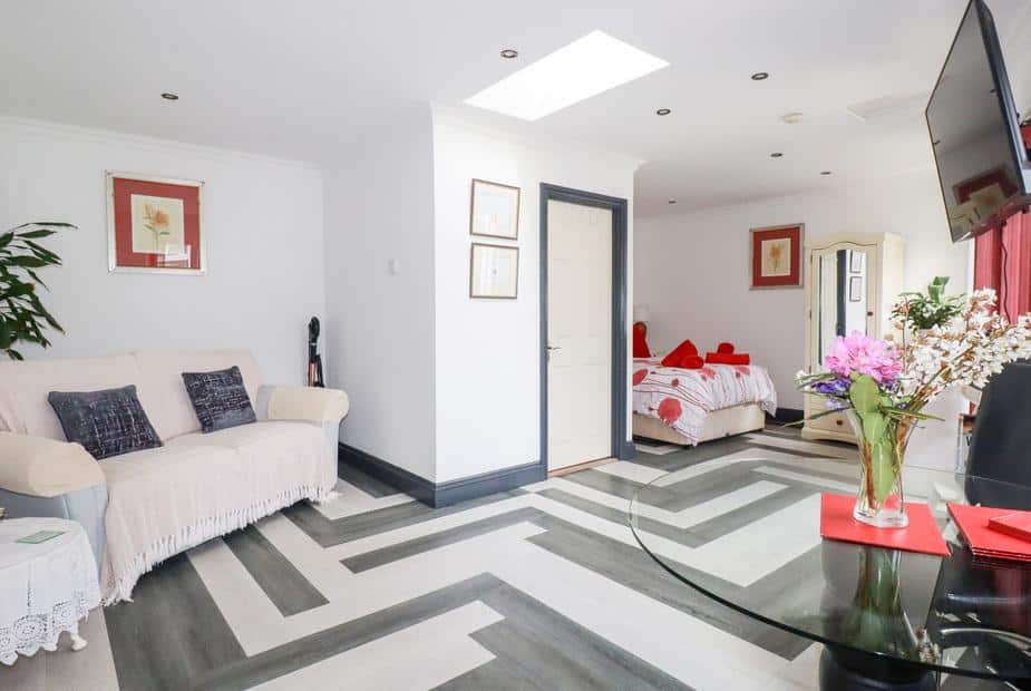 Cottage lounge with sofa, dining table and view into bedroom with double bed