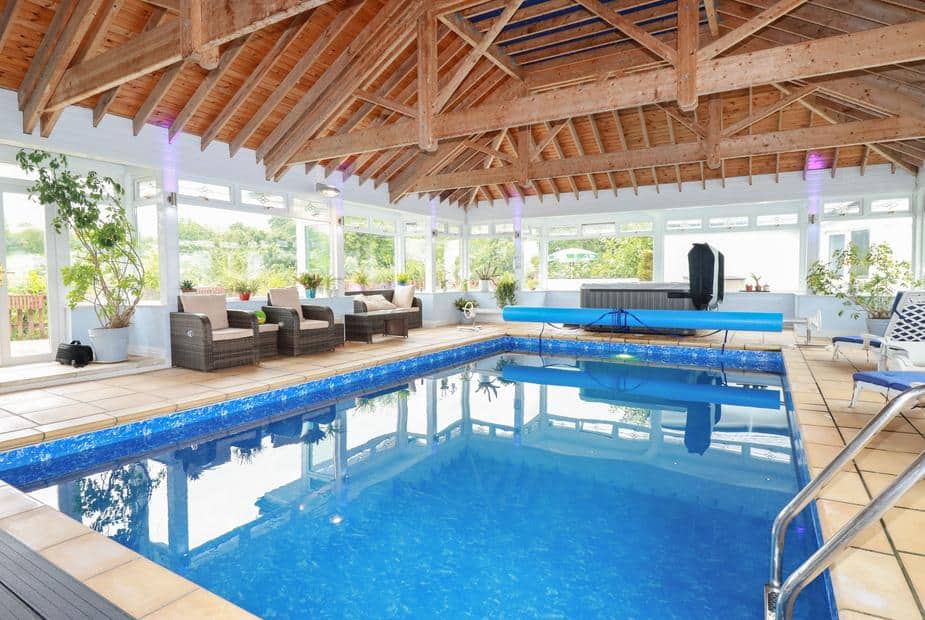 Cottage indoor pool with wicker seating and wooden beamed ceiling