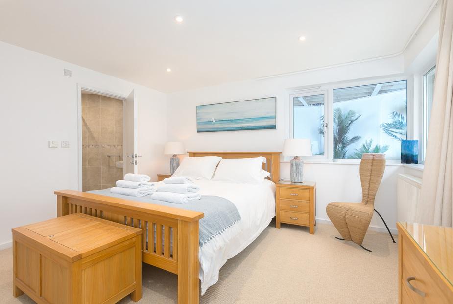 Cottage bedroom with wooden bed, side tables and window overlooking garden plants