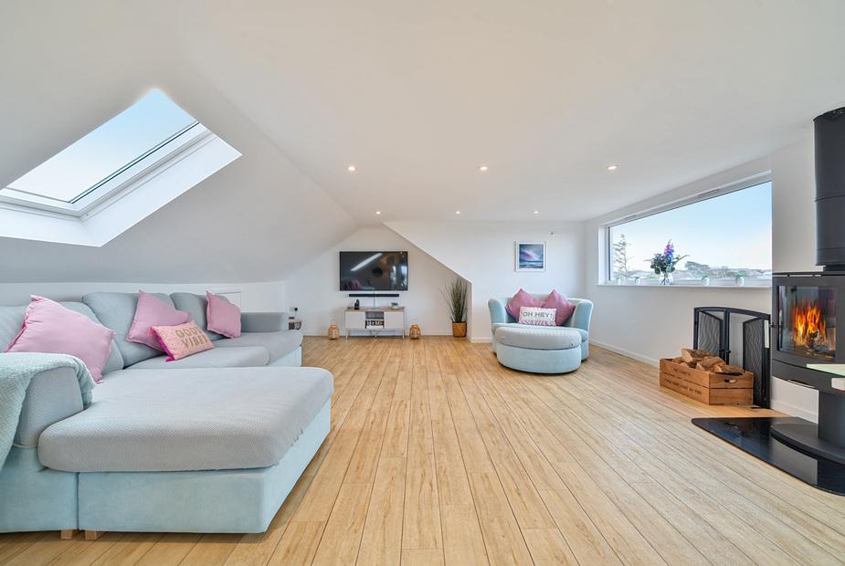 Cottage lounge with skylight, wood burner, corner sofa and TV on wall
