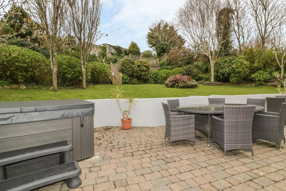 Cottage patio with hot tub, outdoor dining set and view of lawn with trees