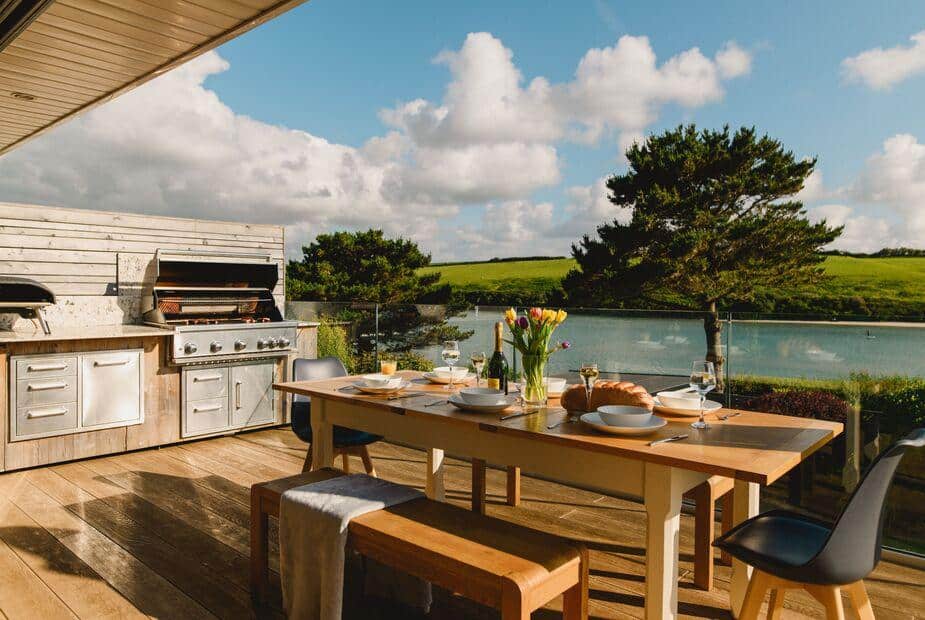 Cottage terrace with outdoor dining table and built-in barbecue overlooking water