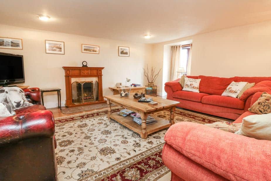 Cottage living room with red sofas, fireplace and wooden coffee table