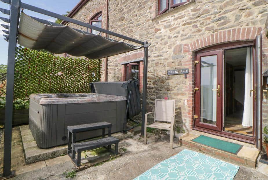 Cottage patio with hot tub and seating by double doors