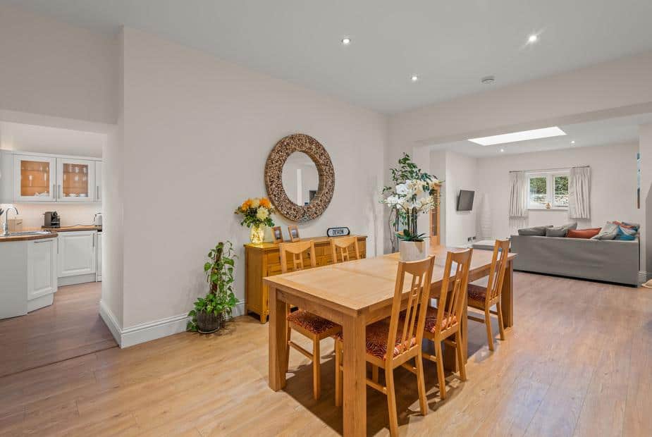 Dining area with six chairs in open-plan cottage next to lounge and kitchen