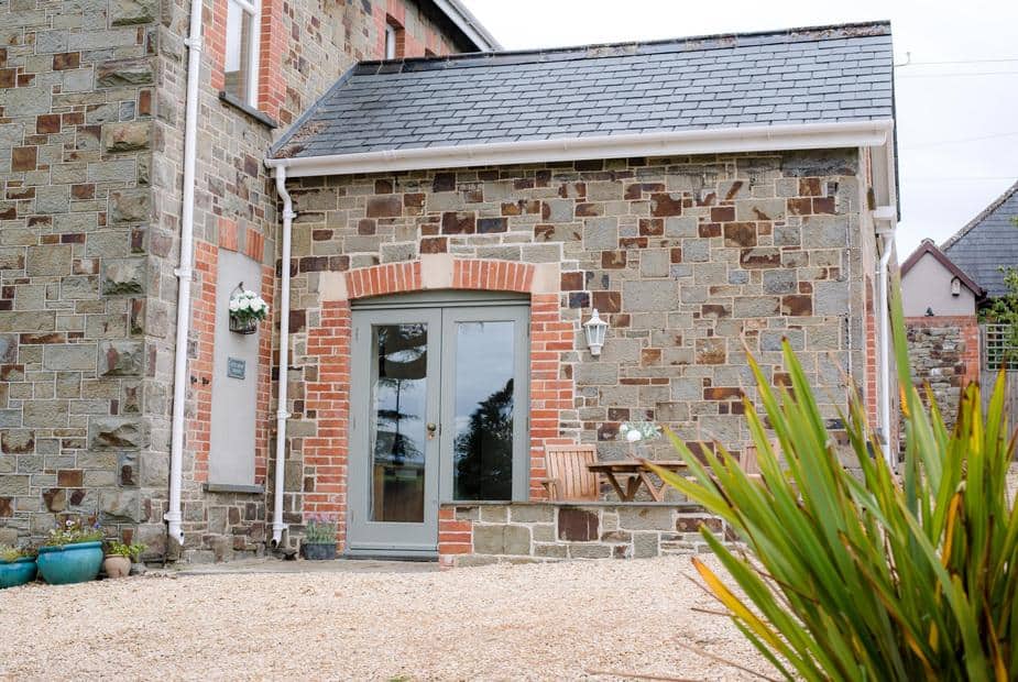 Cottage exterior with stone walls, patio door and small outdoor table with chairs