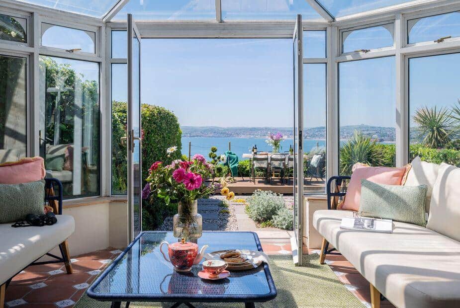 Conservatory in cottage with sea view and patio dining table visible through open doors