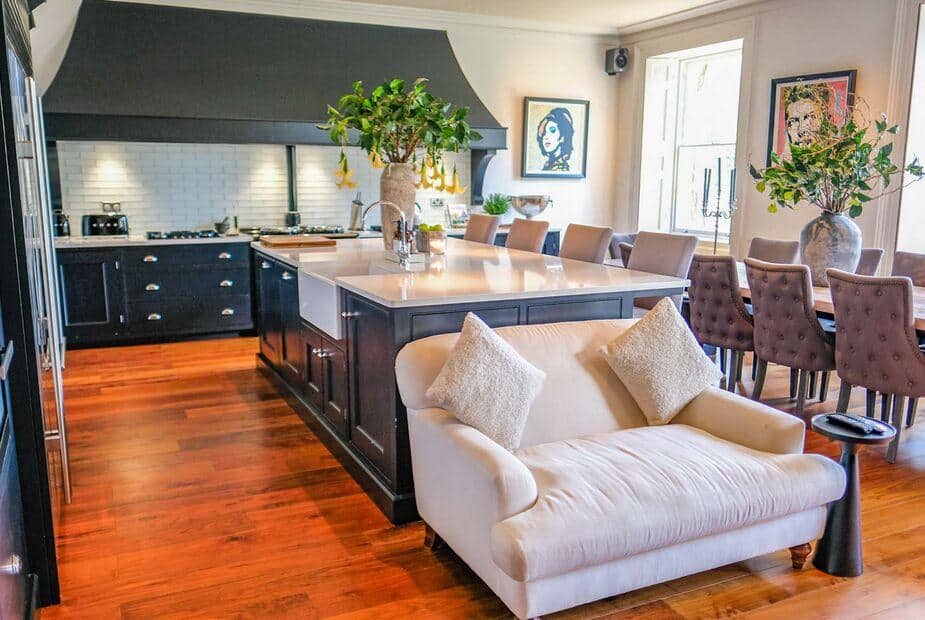 Cottage kitchen with central island, dining table and cream sofa in foreground